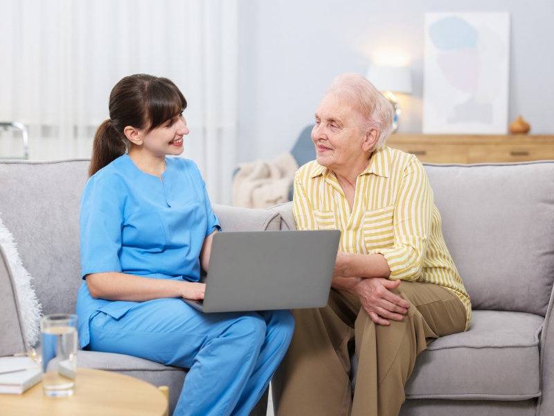 Caregiver providing companionship to elderly woman during home visit