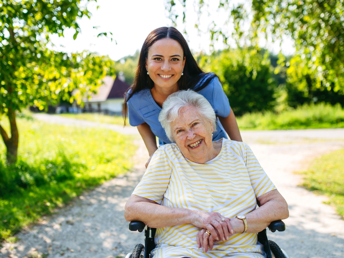 Caregiver assisting a senior couple outdoors with personal care support