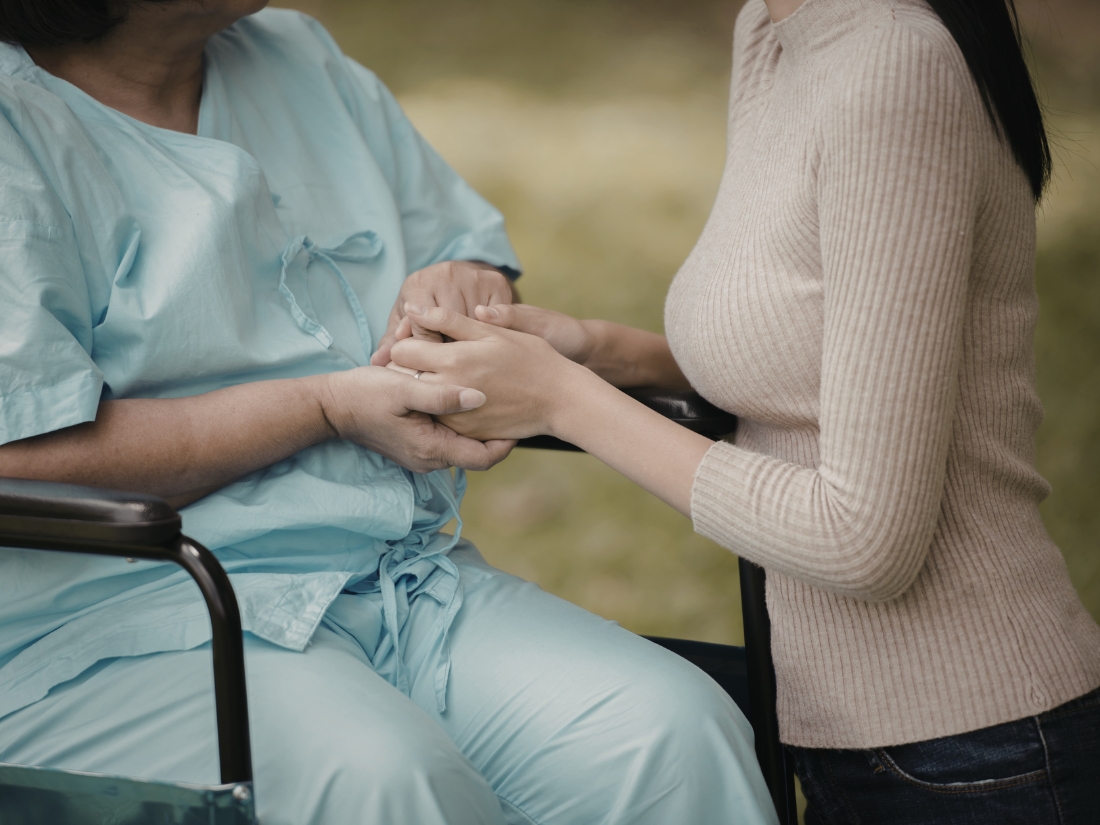 Caregiver holding patient’s hands providing palliative and comfort care